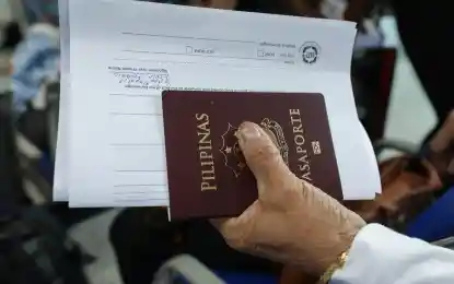 A Filipino man holding his Philippine passport and DFA passport application form.