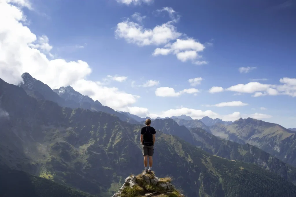 A man stands on a mountain peak, suggesting the challenges of self process his Chinese visa application.