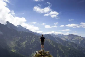 A man stands on a mountain peak, suggesting the challenges of self process his Chinese visa application.