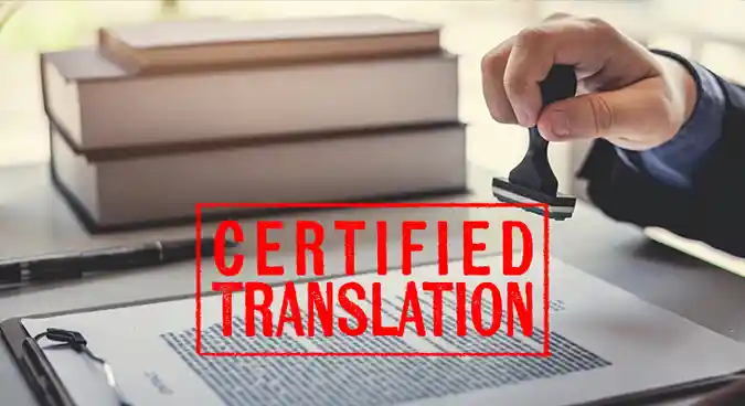A person is holding a stamp, ready to stamp it; the stamp displays the words "certified translation" in red.