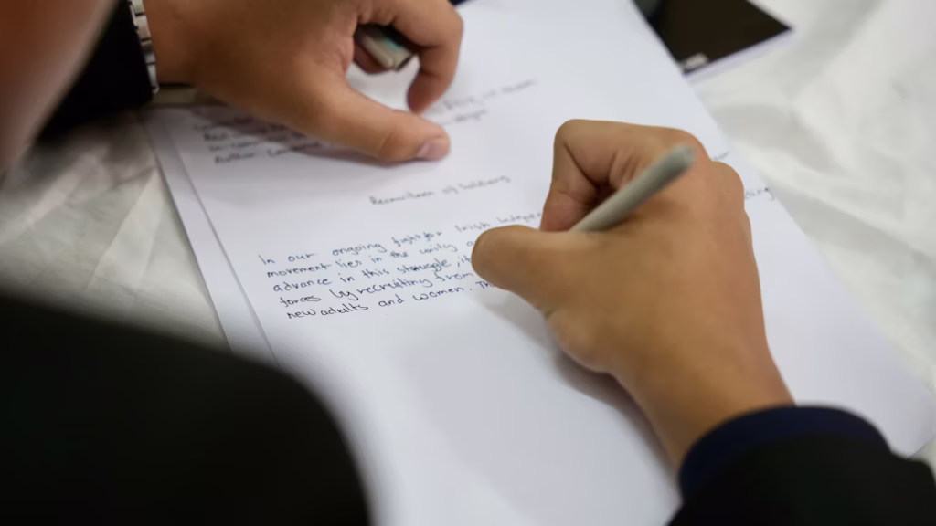 A man is handwriting an invitation letter for a Chinese visa application.
