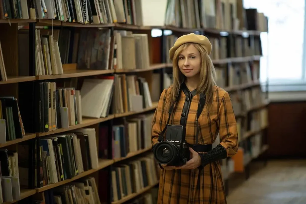 A foreign woman journalist who entered China to work using a J visa in China, holding a camera in the library.
