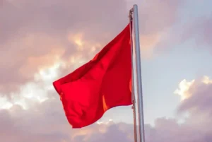 A red flag stands tall in the sky, suggesting things to be aware of when people apply visa for the first time.