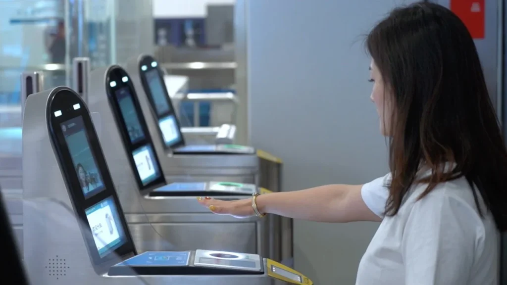 A woman raises her hand to have her palm scanned by a machine to enter China.