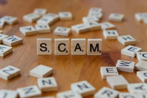 The wooden block with the words "SCAM," suggesting a visa scam involving fake visa in Chinese visa applications.
