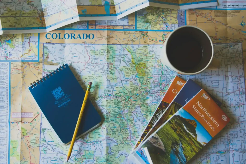 A map with a notebook and a pen is on the table; this person is preparing an itinerary for a Chinese visa application.