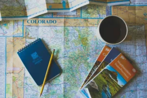 A map with a notebook and a pen is on the table; this person is preparing an itinerary for a Chinese visa application.