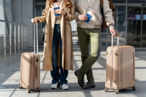 A couple holding their baggage at the airport before their travel, offering travel advices to others.