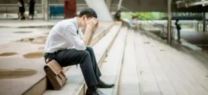 A no job man sits on the ground, worrying about his Chinese visa application sponsor problem.